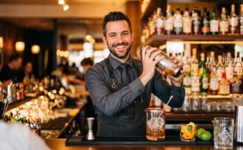 Confident bartender mixing a cocktail behind a bar counter.